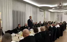 Drugowie OSP Złotniki Kujawskie siedzą po dw&oacute;ch stronach długiego stołu w restauracji. Mężczyzna w ciemnej marynarce i białej koszuli stoi