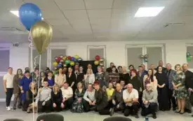 Grupa ludzi ładnie ubranych na zabawie karnawałowej pozuje do zdjęcia.