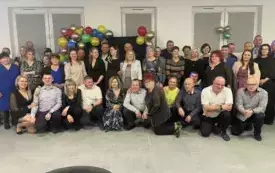 Grupa ludzi ładnie ubranych na zabawie karnawałowej pozuje do zdjęcia.