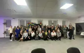 Grupa ludzi ładnie ubranych na zabawie karnawałowej pozuje do zdjęcia.