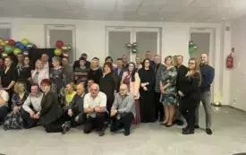 Grupa ludzi ładnie ubranych na zabawie karnawałowej pozuje do zdjęcia.