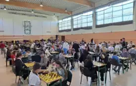 Dzieci siedzą na krzesłach przy stolikach z szachami