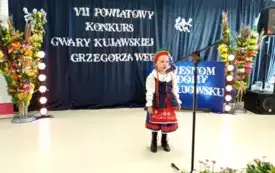Dziewczynka stoi przy mikrofonie urana w str&oacute;j ludowy